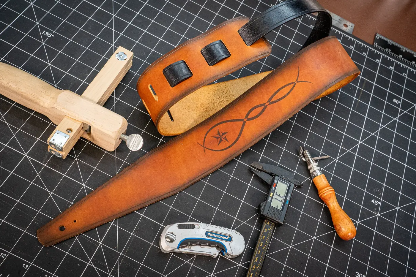 A finished engraved wide strap among the maker's leather tools